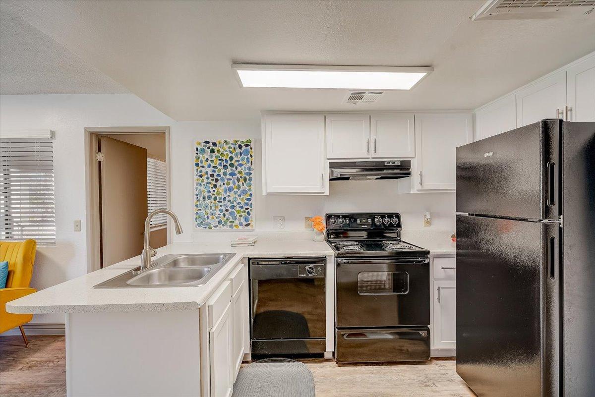 Kitchen peninsula with sink, dishwasher and black refrigerator
