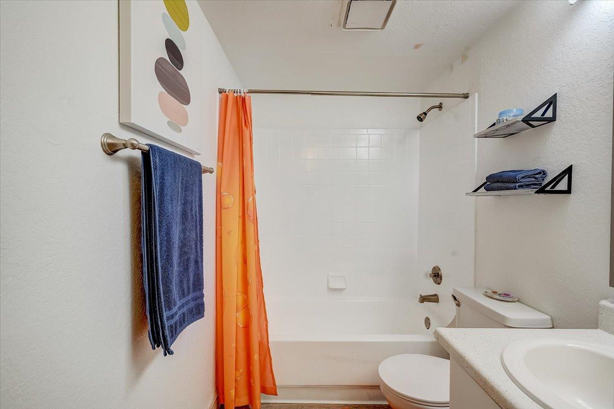 Primary bathroom tub and shower with orange curtain
