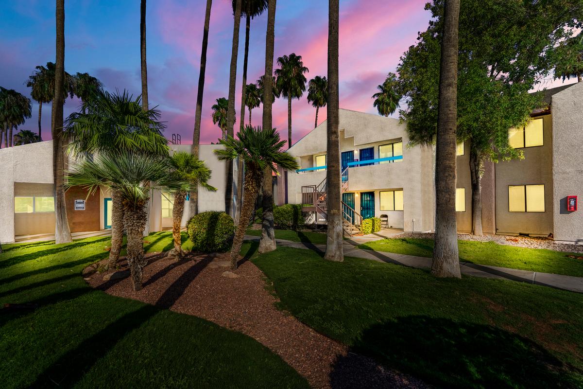 Two-storey apartment buildings, lawn and palm trees at dusk
