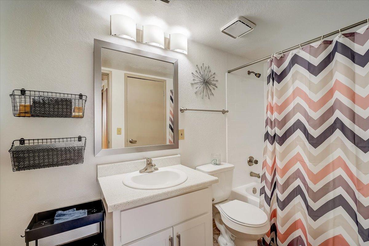 Bathroom with white vanity, wire baskets and chevron shower curtain