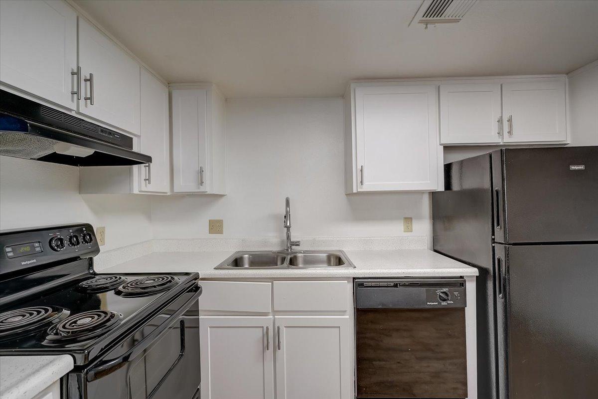 Vacant kitchen, range hood and refrigerator
