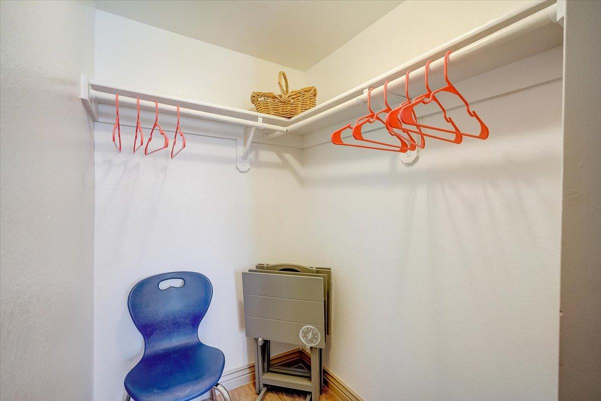 Walk-in closet with shelf and rail, blue chair