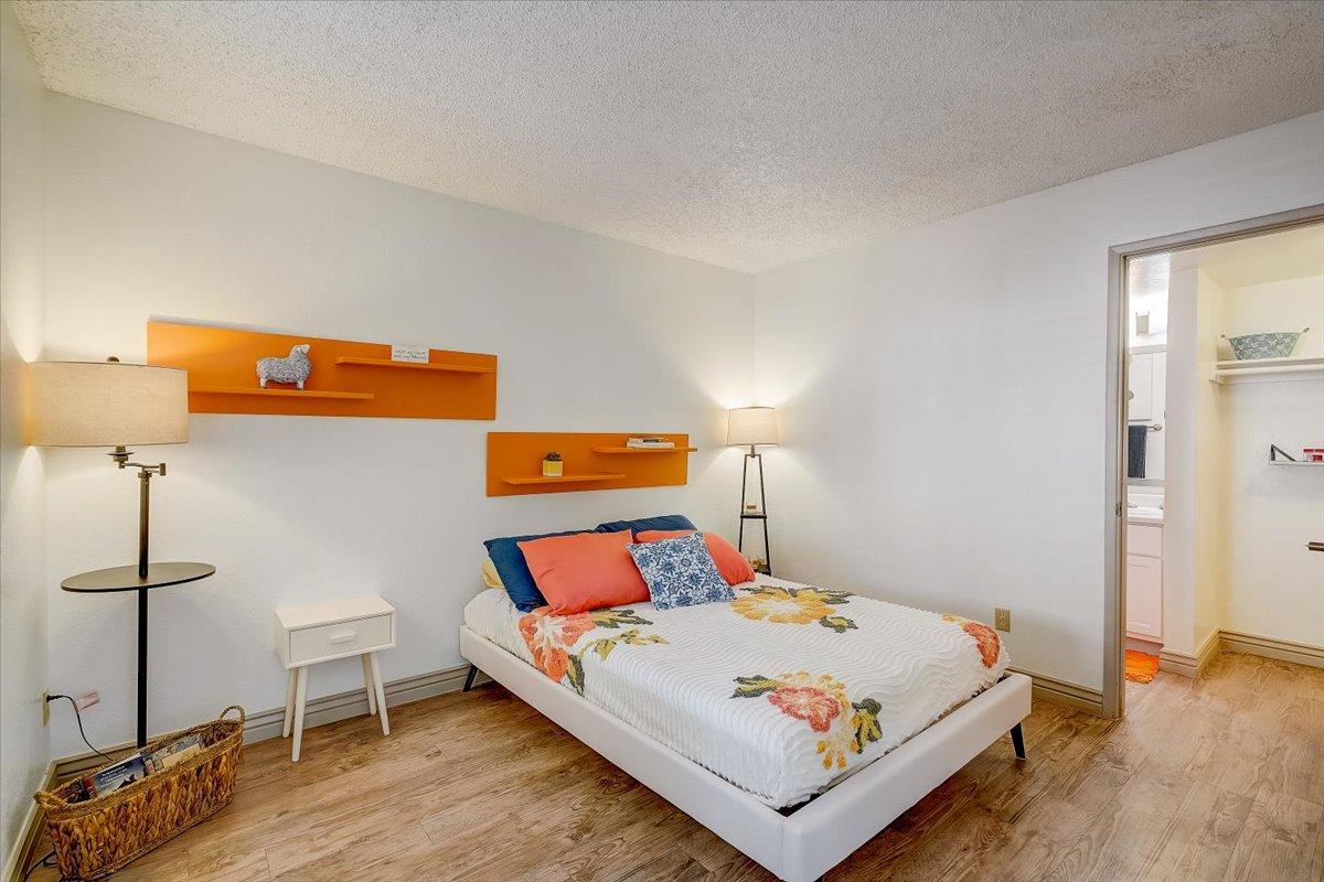 Primary bedroom: bed with floral spread, orange wall shelves, door to the bathroom