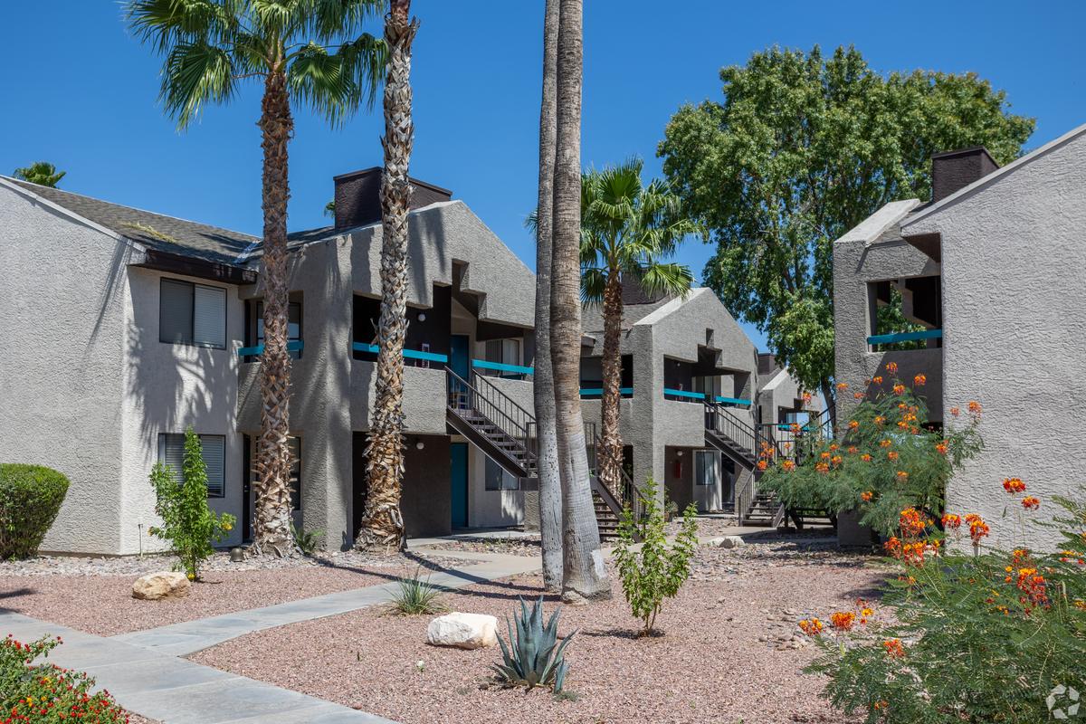Apartment buildings with exterior stairs, palms and flowering desert plants, daytime