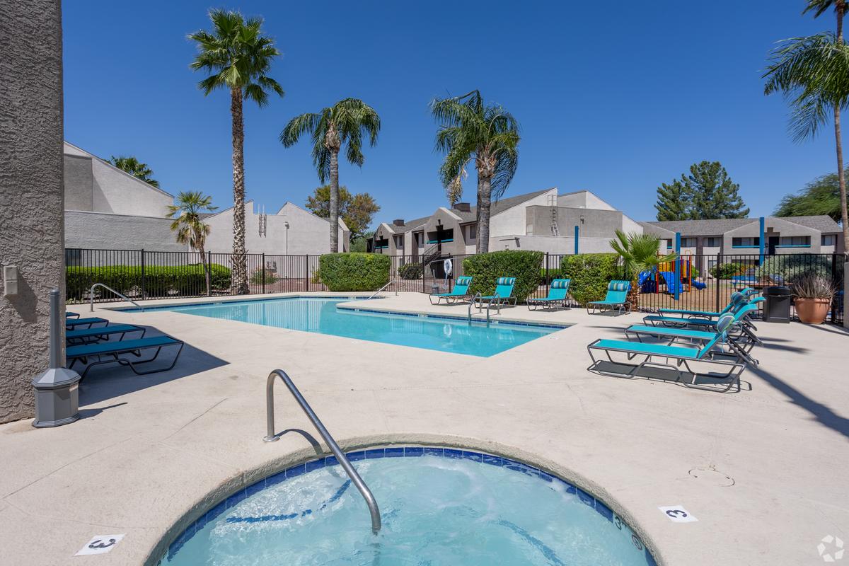 Spa in the foreground, swimming pool and turquoise loungers behind, daytime