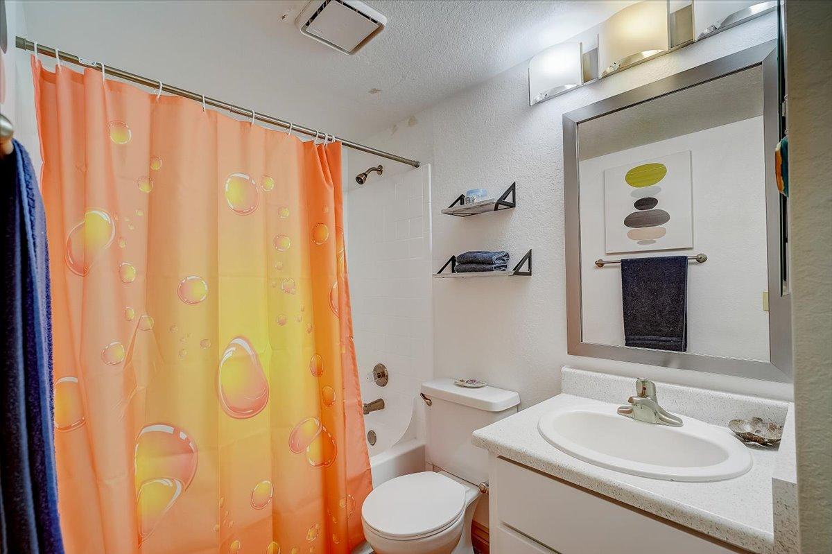 Primary bathroom with orange shower curtain and vanity