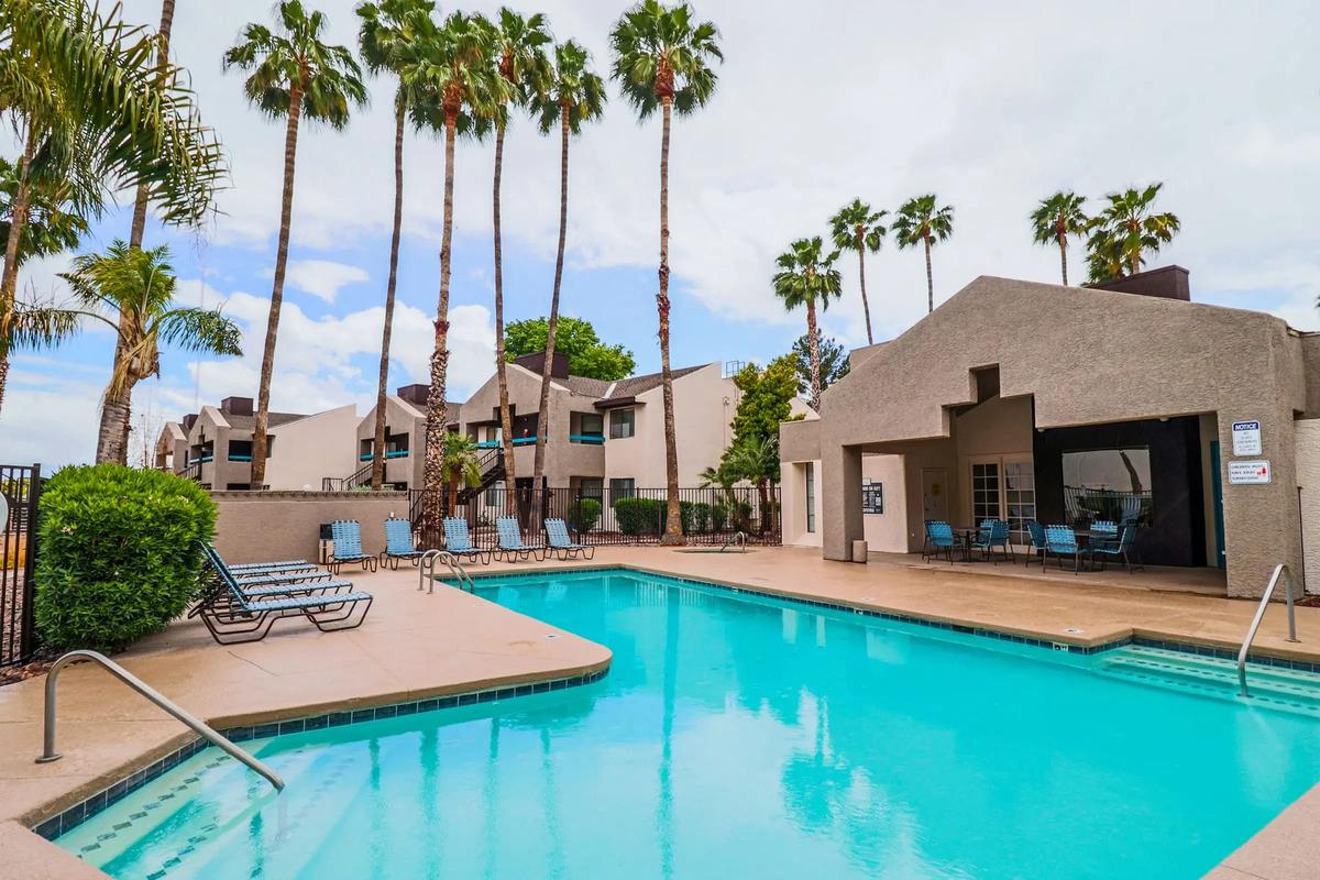Swimming pool and loungers with the clubhouse and apartment buildings behind, daytime