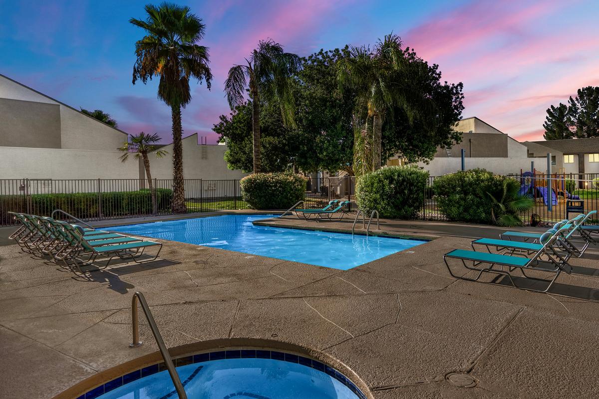 Swimming pool and spa at dusk, loungers on the deck