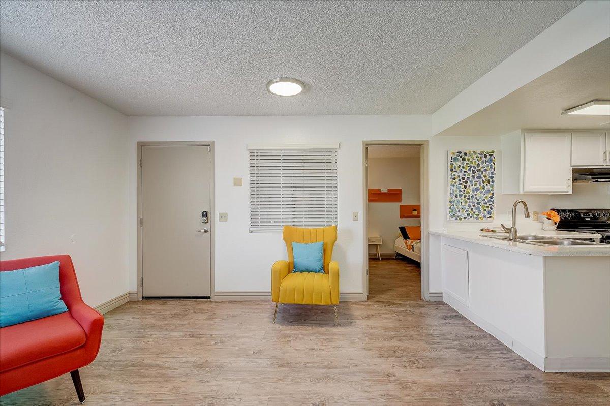 Entry hall with front door, yellow armchair, kitchen counter and the bedroom beyond