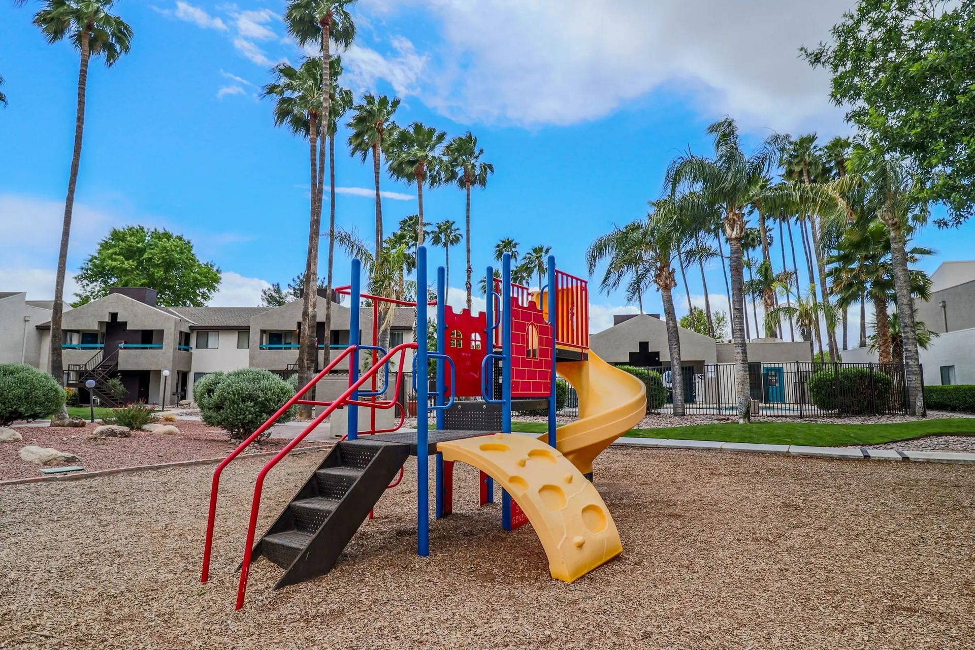 A playground with a yellow slide and red and blue play structures.