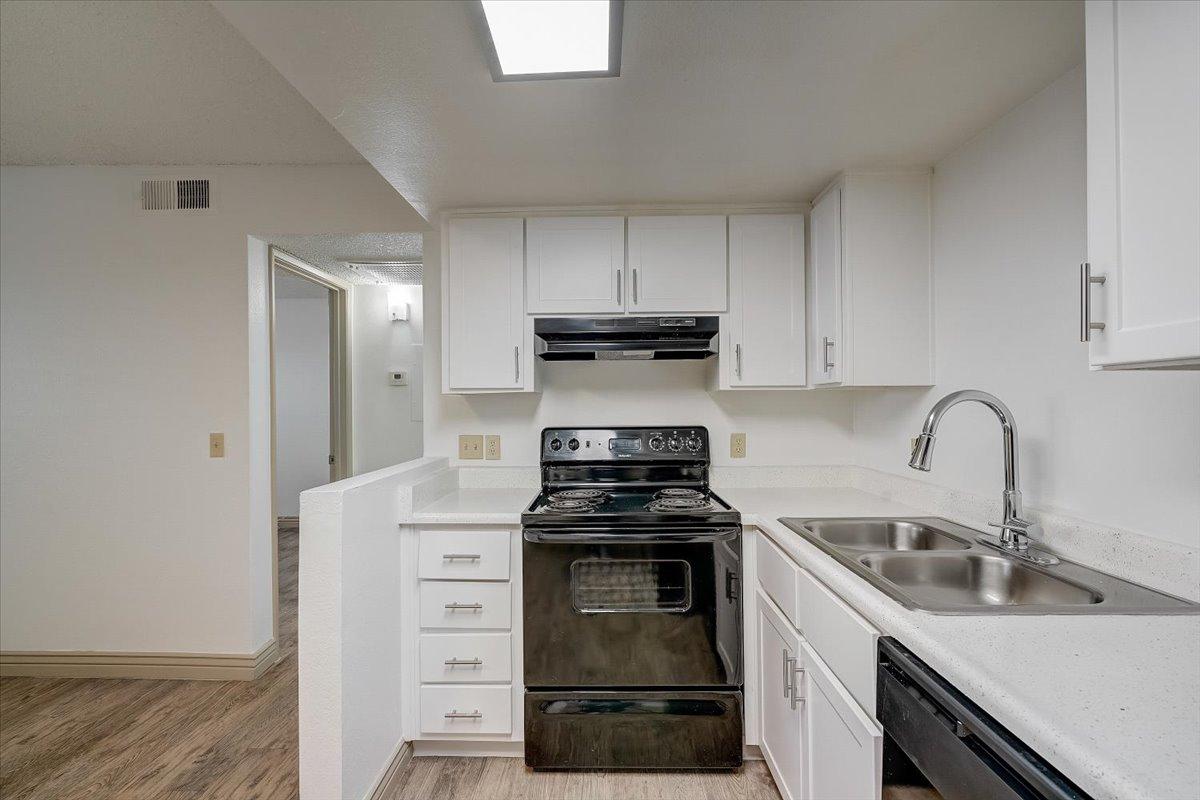 Vacant kitchen with sink and peninsula, hallway beyond