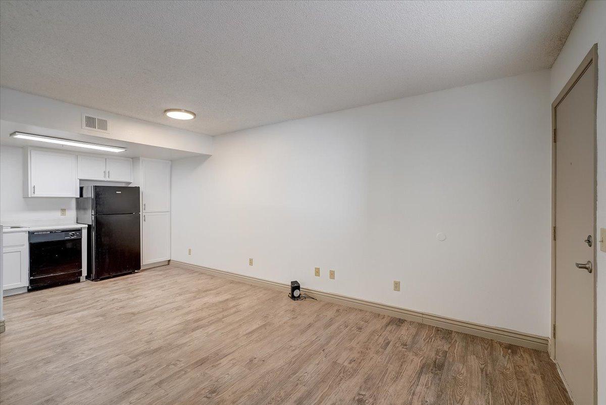 Vacant living room, kitchen at the left, front door at the right