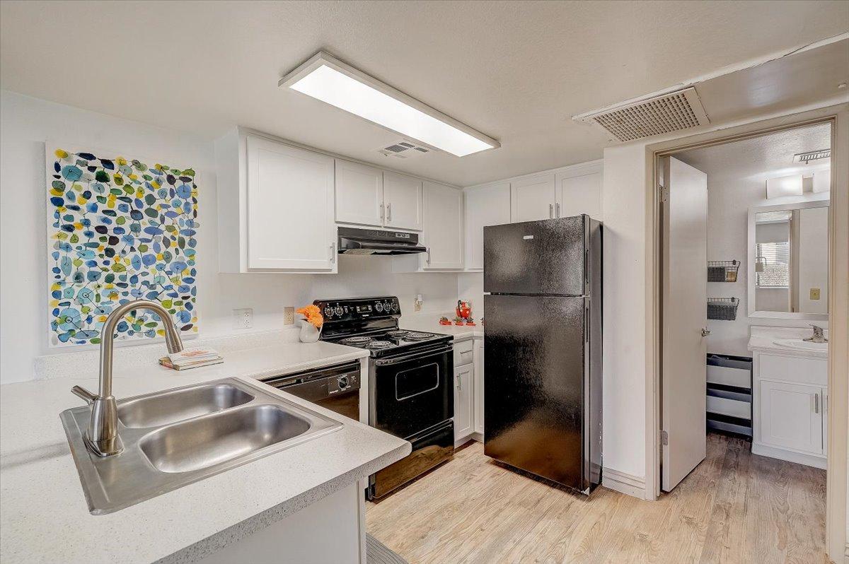 Kitchen sink, black range and refrigerator, hallway to the bathroom