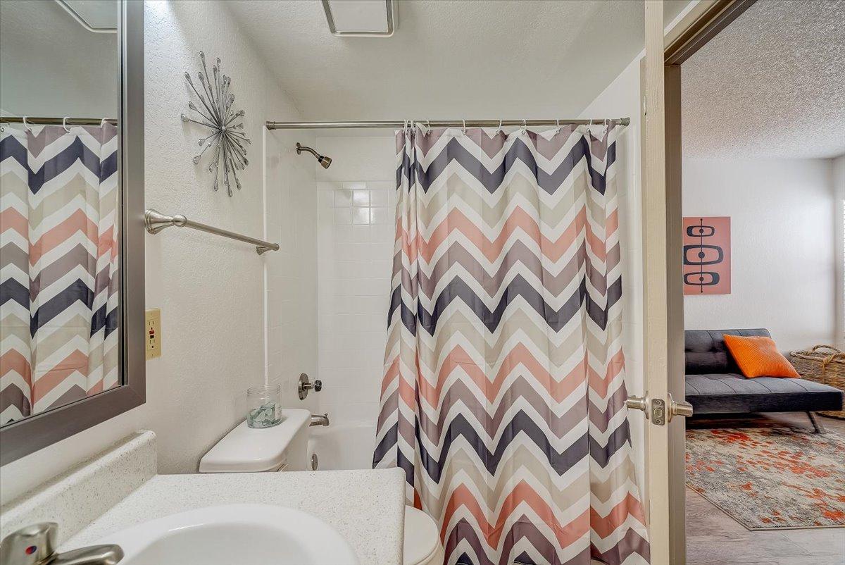 Bathroom with chevron shower curtain looking through to the second bedroom
