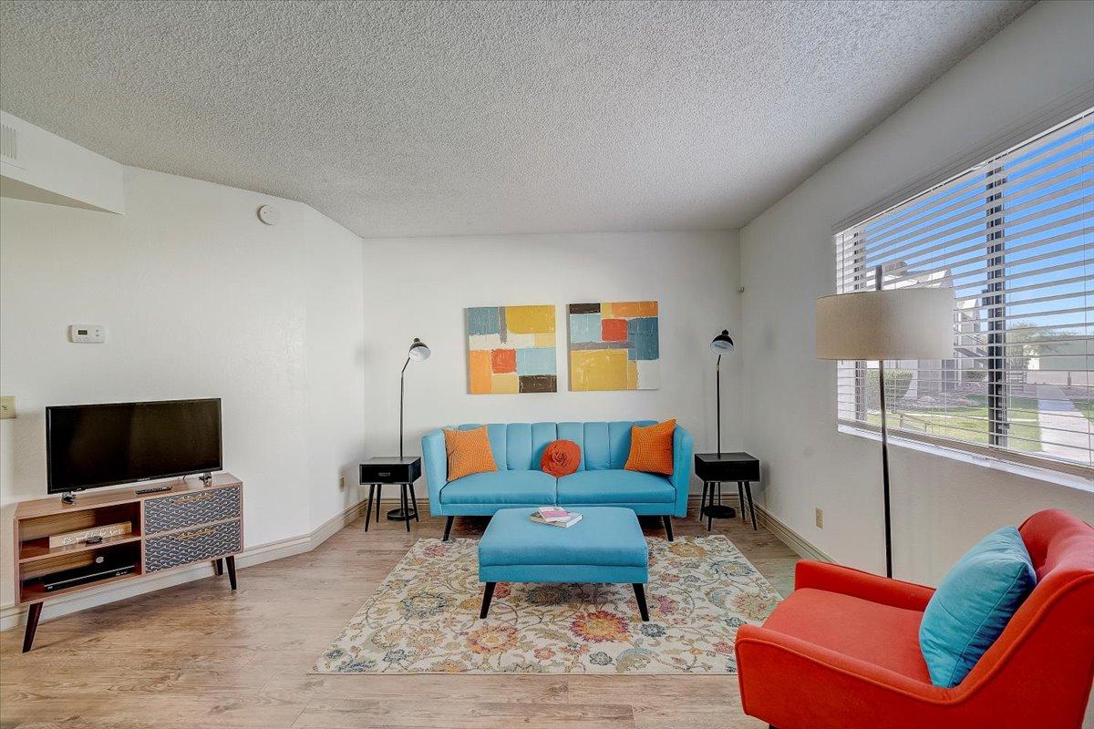 Living room with television, window blinds and blue sofa